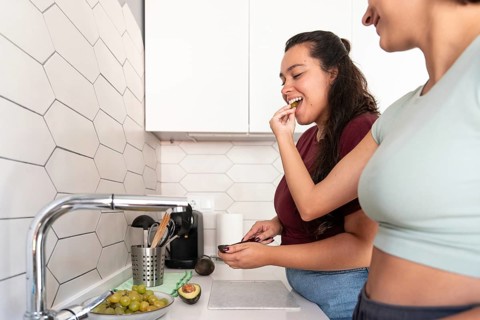 A cheerful lesbian couple shares a coffee break in their stylish kitchen. They enjoy a moment of