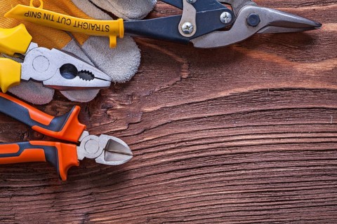 Nippers pliers wire-cutter and construction glove on wood board maintenance concept