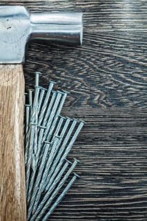 Heap of construction nails claw hammer on wooden board