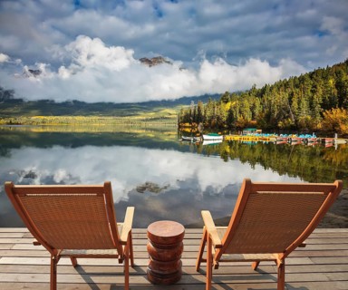 Pyramid Mountain reflected in Pyramid Lake. Two comfortable wooden sun beds for tourists,