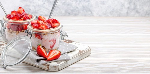 Parfait with Fresh Strawberries, Yoghurt and Crunchy Granola in Transparent Glass Mason Jars on