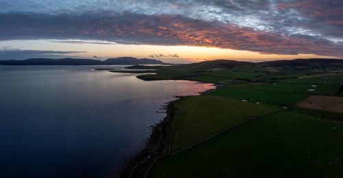 Sunset with cloud band on the coast of Scapa Flow with view to the island of Hoy, drone shot,