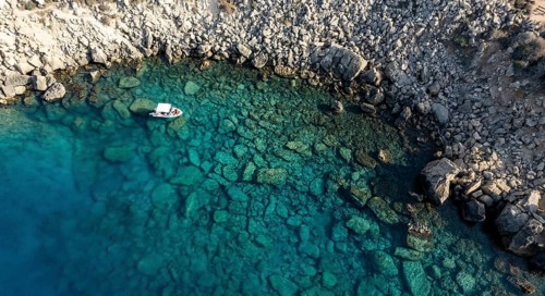 Drone aerial seascape with luxury yacht moored on the coast. Blue water Summer vacations in the sea