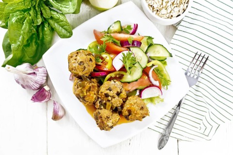 Minced meatballs with spinach, oatmeal and green onions in tomato sauce, vegetable salad in a