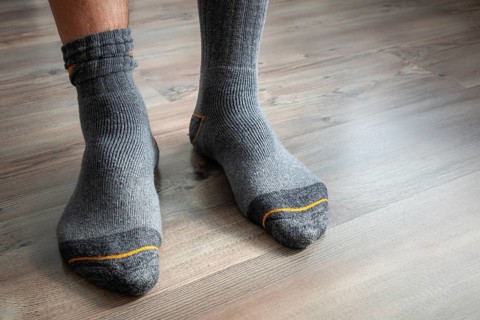 An image of male feet in grey socks on a wooden floor