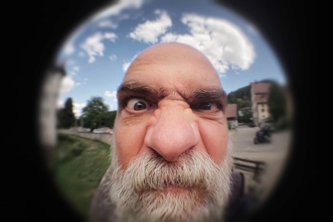 An image of an angry man looking to a peephole door