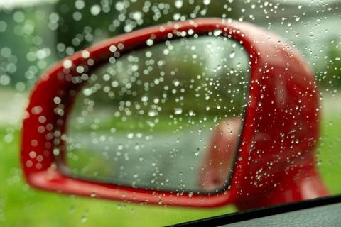 Red exterior mirror of a car in the rain