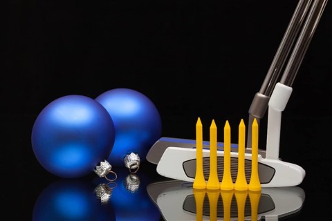 Christmas decoration and two golf putters on a glass desk