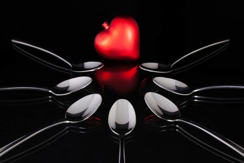Teaspoons and love symbol on the black glass desk