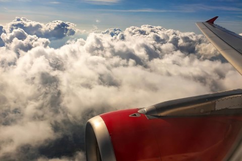 A colour landscape image looking out through airplane window showing land, cloud and sky