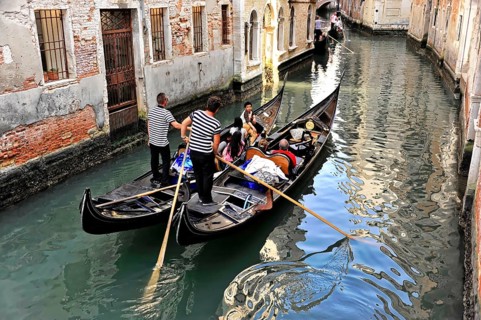 Venice, Veneto, Italy, Europe, Gondolas manoeuvre through a narrow canal, surrounded by old brick