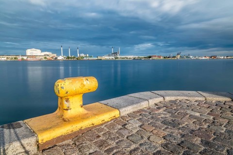 Scenic view of the skyline of Copenhagen at sunset from dock with yellow bollard on foreground