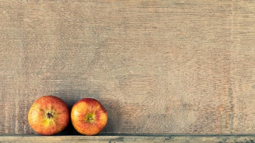An image of a wooden background with two small apples