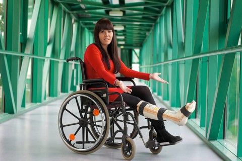 Young woman with plaster leg sits in a wheelchair Austria