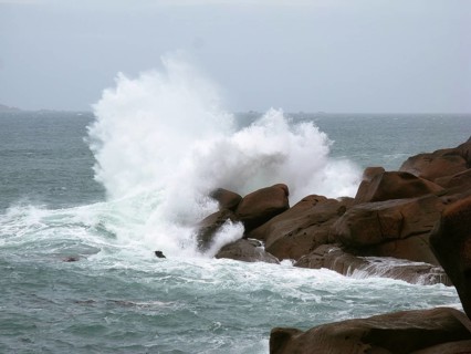 Strong surf waves break on a rocky outcrop