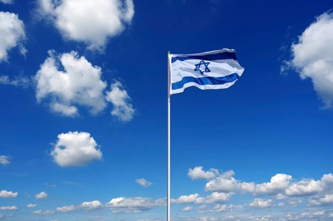 Flag of Israel fluttering in the blue sky with cumulus clouds