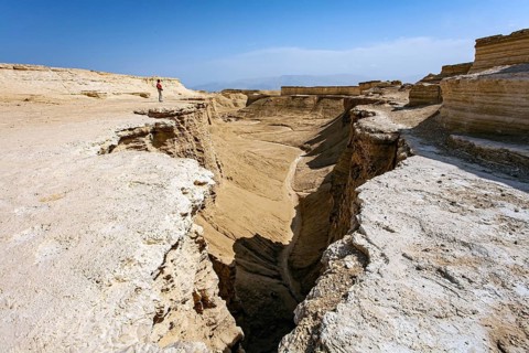 Woman tourist in a red sweater admires the landscape. The Judean Desert. Israel. Interesting walk