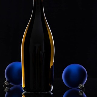 The bottle of red wine and Christmas decoration on a black glass desk