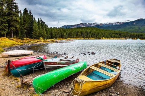 Multicolored boats and canoes dry on the lakeside. Cold cloudy fall day in the Canadian Rockies.