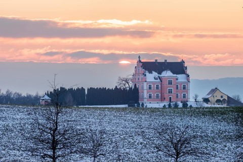A castle in the middle of snow-covered fields at sunset with a cloudy sky, Freudental Castle,