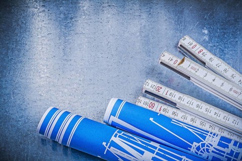 Blue rolled construction drawings wooden meter on scratched metallic background