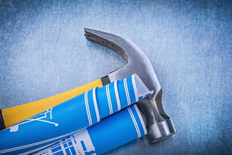 Blue rolled blueprints claw hammer on metallic background construction concept