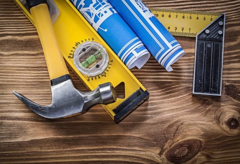 Blue blueprints construction level try square claw hammer on wooden board
