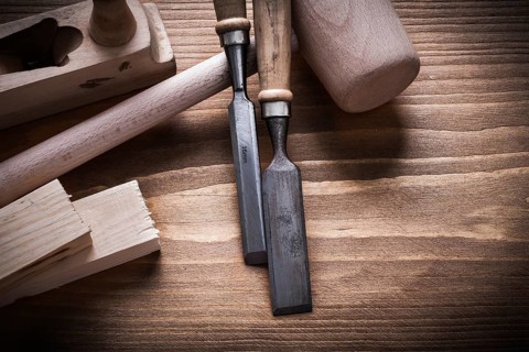 Wooden hammer stud planner flat chisels on wood board construction concept