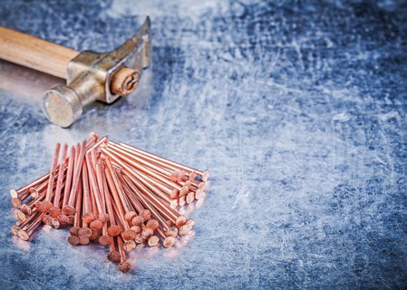 Vintage claw hammer heap of brass construction nails on metallic background