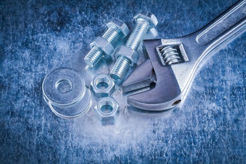 Metal adjustable wrench bolt washers screw-nuts and screwbolts on scratched metallic background