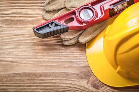 Building helmet protective gloves construction level on wooden board