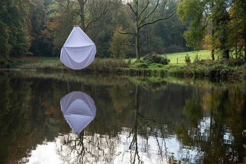 Reflecting water pond in a park with a white bed sheet hanging in a tree