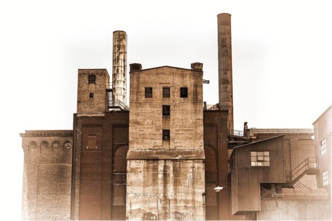 Old power plant building with brick, concrete and metal walls, retro sepia toning