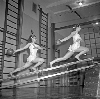 Gymnastics in the 1940s. Two young women are balancing on gymnasium equipment and at the same time