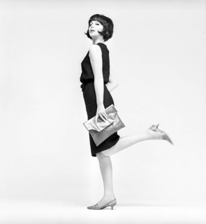 In the 1960s. A model in a typical 1960s outfit photographed in a studio. A black popular dress in
