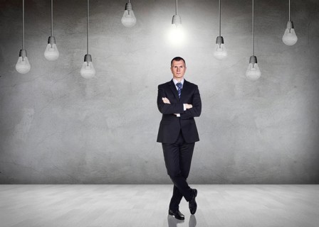 Businessman stands in a gray room with hanging bulbs