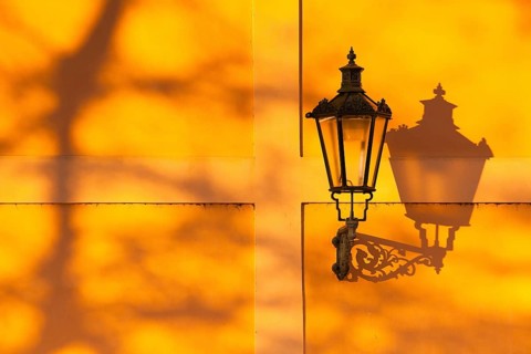 Detail of retro street light on the wall at sunset. Prague, Czech Republic