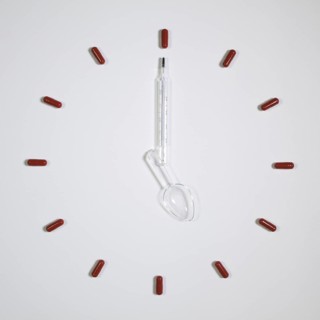 Time - Clock of twelve pills, medical thermometer and plastic spoon