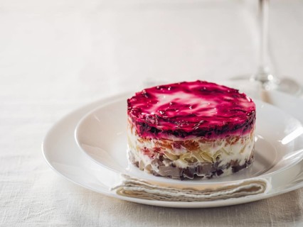 Layered salad herring under fur coat on table. Portion of traditional russian salad with herring,