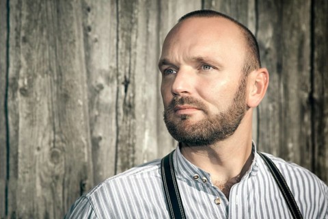 A traditional bavarian man in front of a wooden background