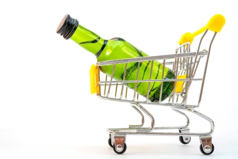 Selling alcohol in a store. Green bottle in a supermarket cart. Drink in a green bottle