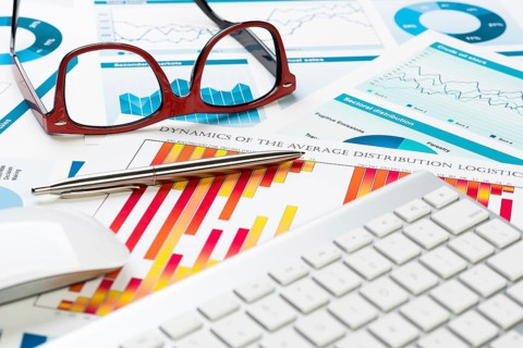 Business workplace with keyboard glasses and financial documents on table