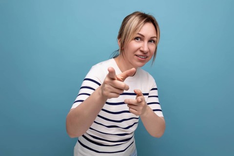 Nahaufnahme einer energetischen blonden jungen frau in einem gestreiften pullover auf einem blauen