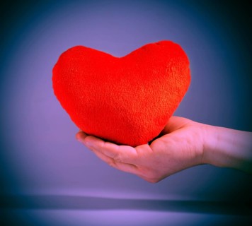 Vintage look red plush heart. Hand holding red heart