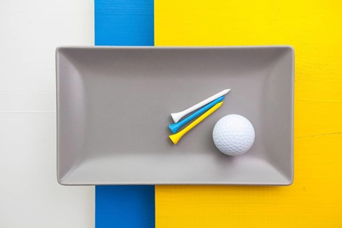 Gray ceramic dish with golf equipments on over white, blue and yellow wooden table, rectangle dish