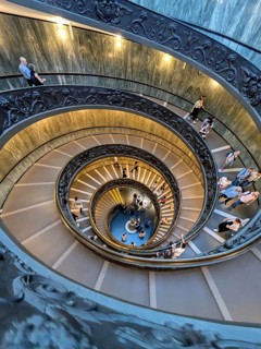 Aerial view of a busy spiral staircase with people ascending and descending, highlighting the