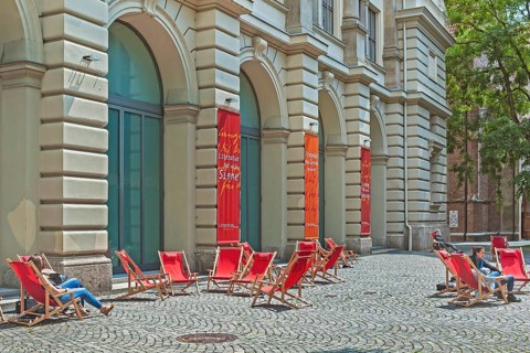Red deckchairs and advertising banners on cobblestones in front of the Literaturhaus, Munich,
