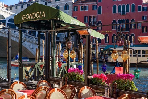 View of the Grand Canal, Rialto Bridge, and gondolas from outdoor restaurant seats, Venice, Italy