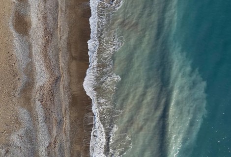 Drone aerial view of stormy ocean waves breaking on a sandy beach. Nature background