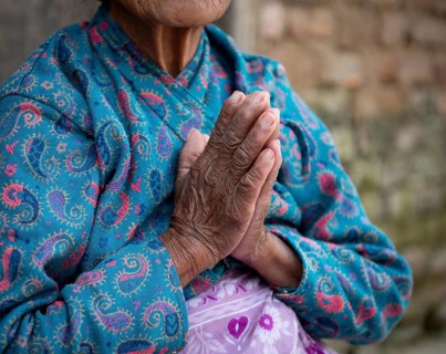 Unrecognized elder nepalise woman wearing blue cloths crossing her wrinkled hands